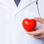 Kiedy udać się do kardiologa? Na zdjęciu lekarz trzyma czerwone serce.