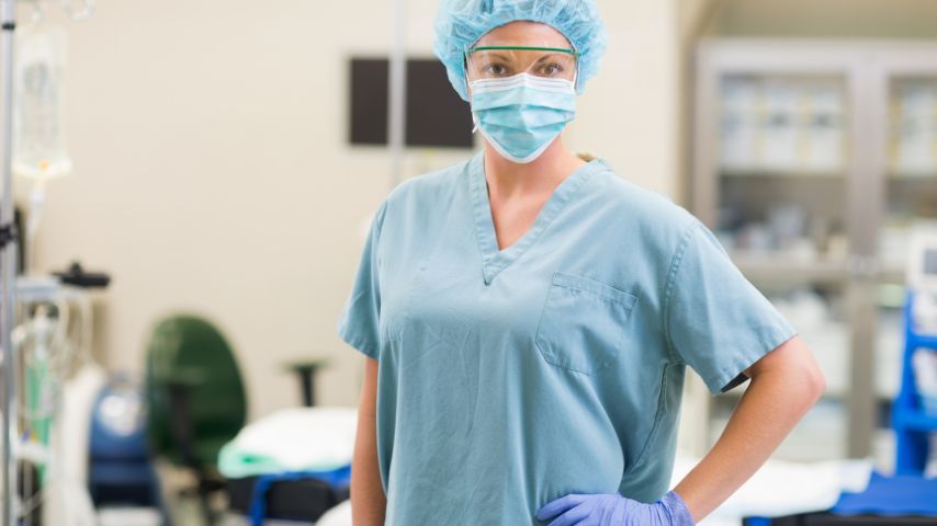 Anestezjolog w okularach medycznych i masce pozujący na sali zabiegowej.