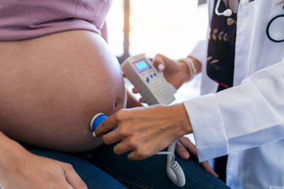 Lekarz wykonujący USG Dopplera na brzuchu ciężarnej kobiety.