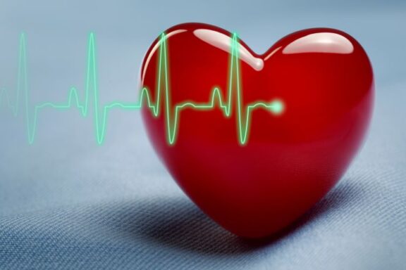 Rys elektrokardiogramu i trójwymiarowe serduszko w tle.