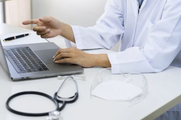 Jak założyć Internetowe Konto Pacjenta? Na zdjęciu lekarz przy laptopie.