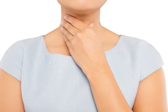 Ujęcie kobiety trzymającej się za szyję w miejscu, w którym występuje tarczyca.