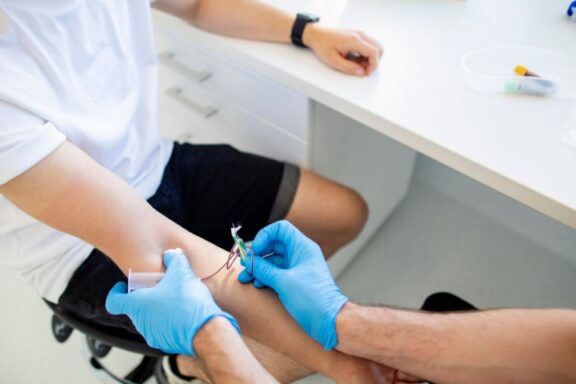 Ujęcie momentu pobierania krwi mężczyzny przez osobę w rękawiczkach.