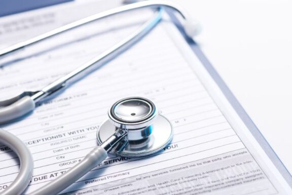 Wydanie dokumentacji medycznej pacjentowi; na zdjęciu dokumentacja medyczna, a na niej stetoskop.